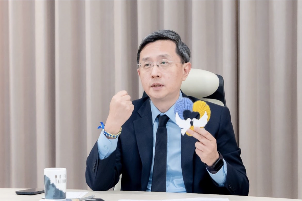 李淳展示由戰區兒童在防空洞避難時製作的藍黃相間手環及鑲有和平白鴿的心型手工藝,並表示台灣將與烏克蘭人民同在,共同對抗威權主義的擴張/圖:外交部提供